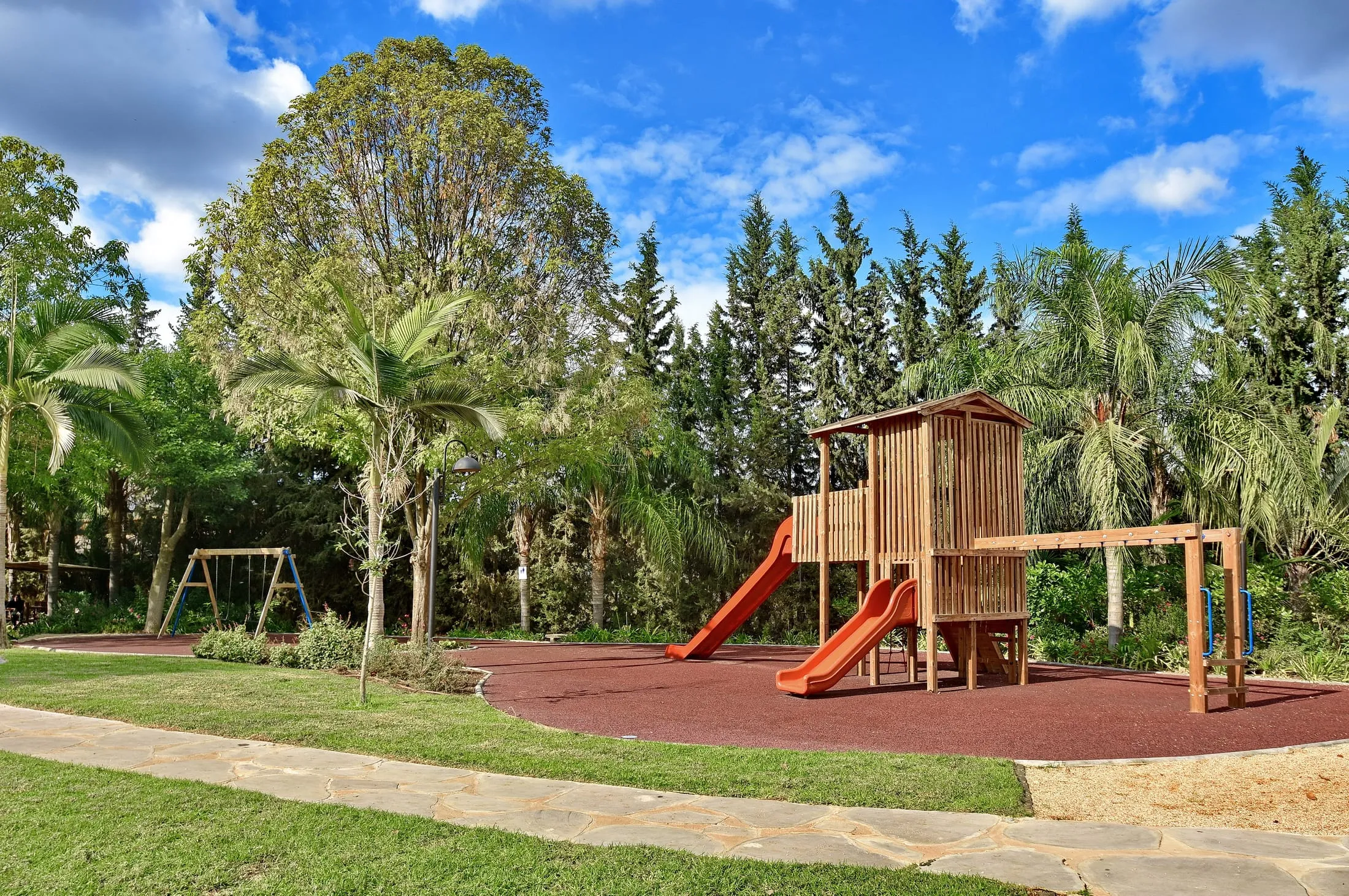 Wooden play tower with orange slides in the landscaped playground area